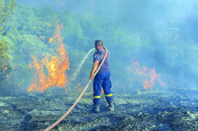 A firefighter tries to extinguish a wildfire burning near the village of Asklipieio, on the island of Rhodes yesterday.  (Reuters)