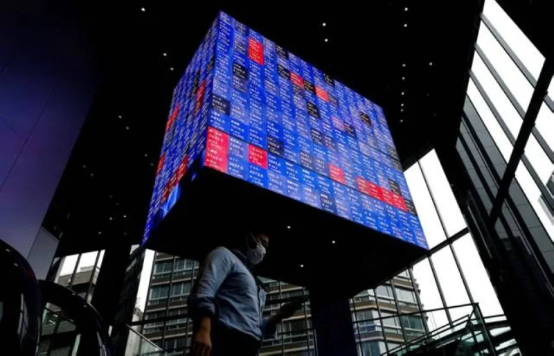 A man walks under an electronic screen showing Japan's Nikkei share price index inside a conference hall in Tokyo, Japan June 14, 2022. REUTERS/Issei Kato
