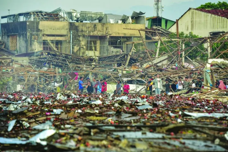 
People look at the aftermath of destroyed homes after an explosion ripped through a firework warehouse, killing nine people and injuring more than 100, in Sungai Kolok district in the southern Thai province of Narathiwat. 
