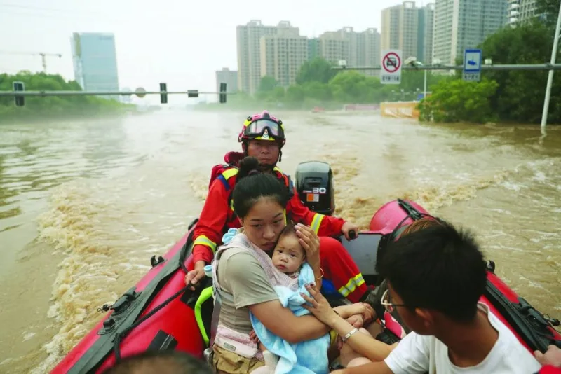 
A woman holds a baby, as rescue workers evacuate residents stranded by floodwaters, following heavy rainfall in Zhuozhou, Hebei province, China, yesterday. 