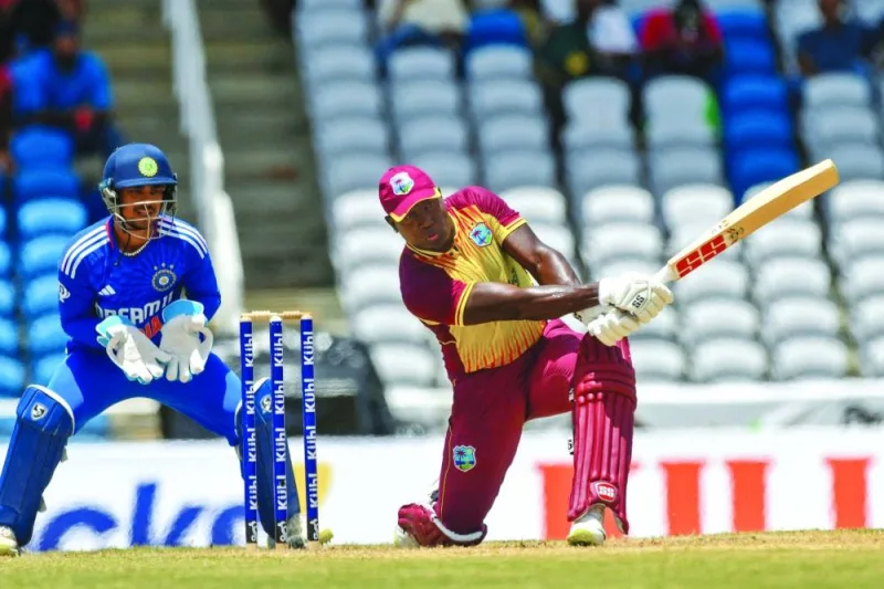 Rovman Powell of West Indies hits a boundary as wicketkeeper Ishan Kishan (left) of India watches during the first T20I match at the Brian Lara Cricket Academy in Tarouba, Trinidad and Tobago, on Thursday. (AFP)