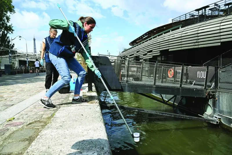 An employee of the company Fluidion collects a sample of water from the Seine to analyse its composition ahead of the 2024 Paris Olympics, near the Pont Alexandre III in Paris, on Friday. (AFP)