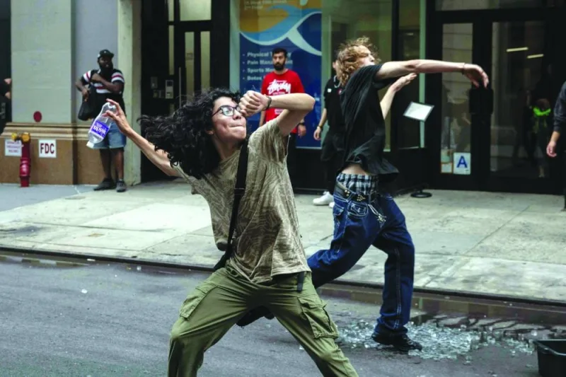 
A rioter aims a water bottle at police officers during riots sparked by Cenat. 