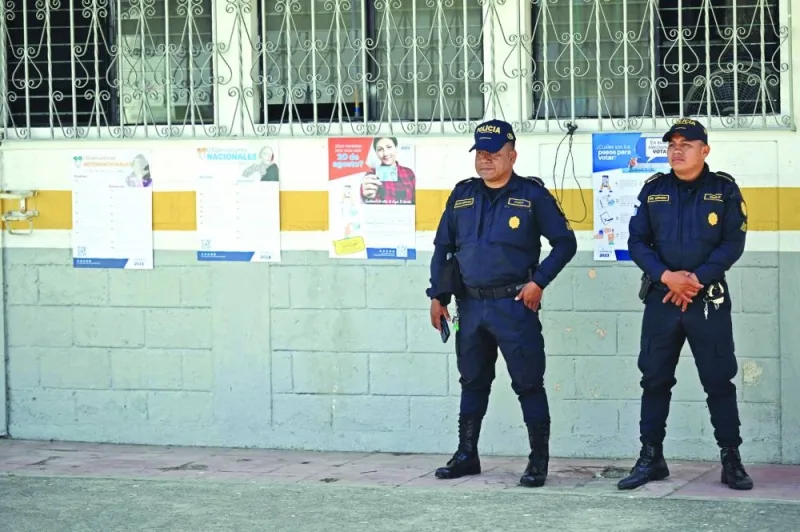 
Police officers stand guard outside a school where polling stations are being set up in Puerta Parada village, Santa Catarina Pinula, Guatemala. 