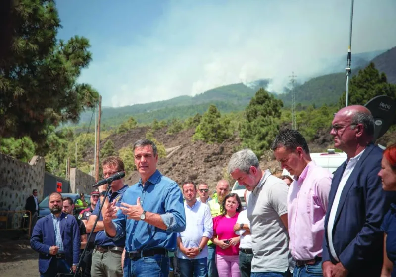 Spain’s acting Prime Minister Pedro Sanchez, flanked by President of the Government of the Canary Islands Fernando Calvijo (fourth right), speaks during a visit to the emergency units’ advanced control post in Arafo, on Tenerife island on Monday as smoke of a huge wildfire is seen in the background. (AFP)