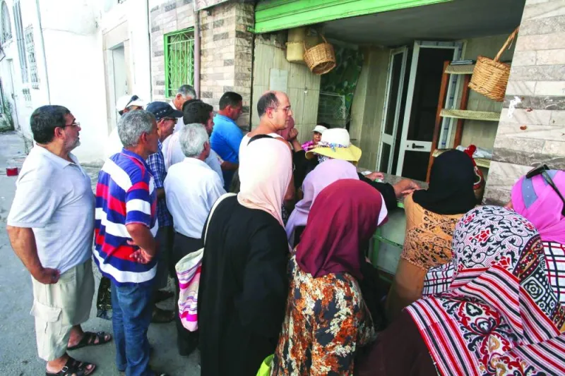 
People queue at a bakery selling subsidised bread in Tunis. 