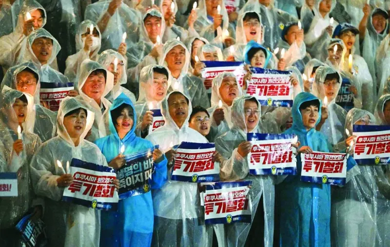 
South Korea’s main opposition Democratic Party members hold electric candles and signs reading “Withdraw the dumping of Fukushima contaminated water!” during a rally against Japan’s plan to release treated water from the Fukushima nuclear plant, at the National Assembly in Seoul yesterday. 