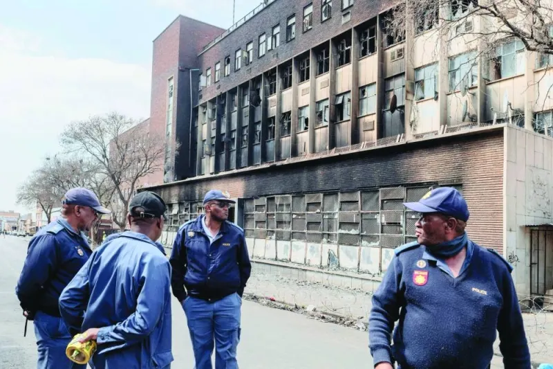 
South African Police Service officers stand at the scene of a burned apartment block in Johannesburg, yesterday. 
