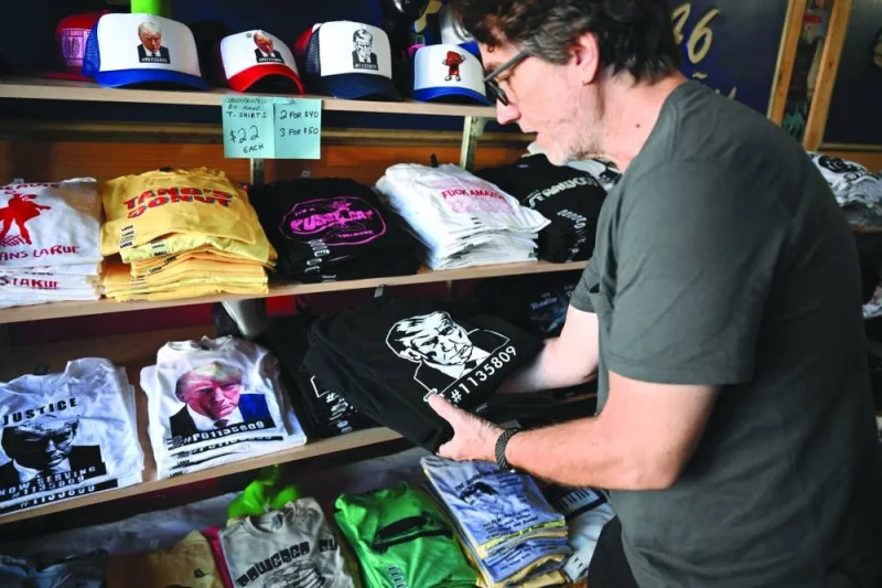 
Employee Todd Moss puts Trump mug shot tee shirts on the shelf at Y-Que shop in Los Angeles, California last month. Store owner Bill Wyatt makes tee shirts for Trump fans and foes alike in the hope of capturing both sides of the market for the historic Fulton County Sheriff’s office mug shot of the former US president. (AFP) 