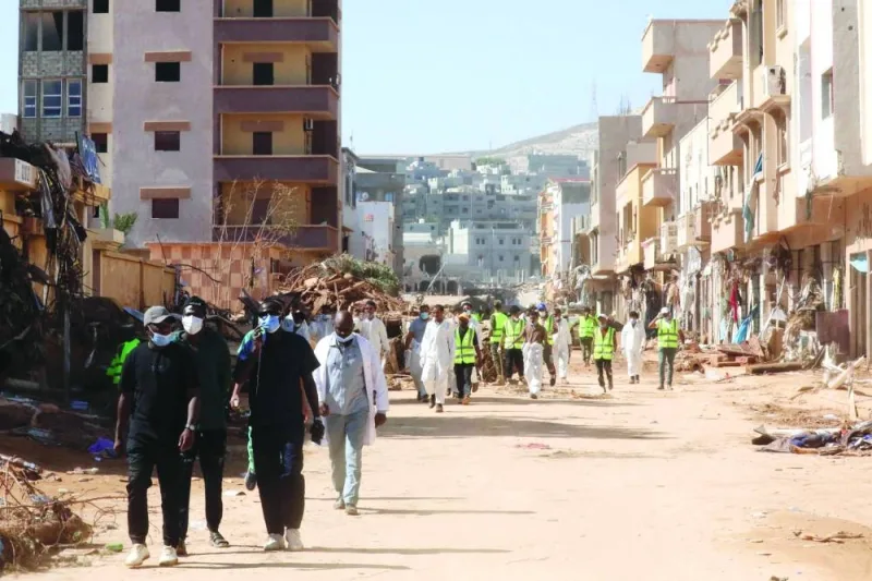 
Volunteers walk past damaged homes after the Mediterranean storm “Daniel” hit Libya’s eastern city of Derna, yesterday. 