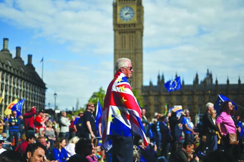 
A protester wearing as a cape a modified Union Jack flag with stars like the EU flag stands in the crowds. 