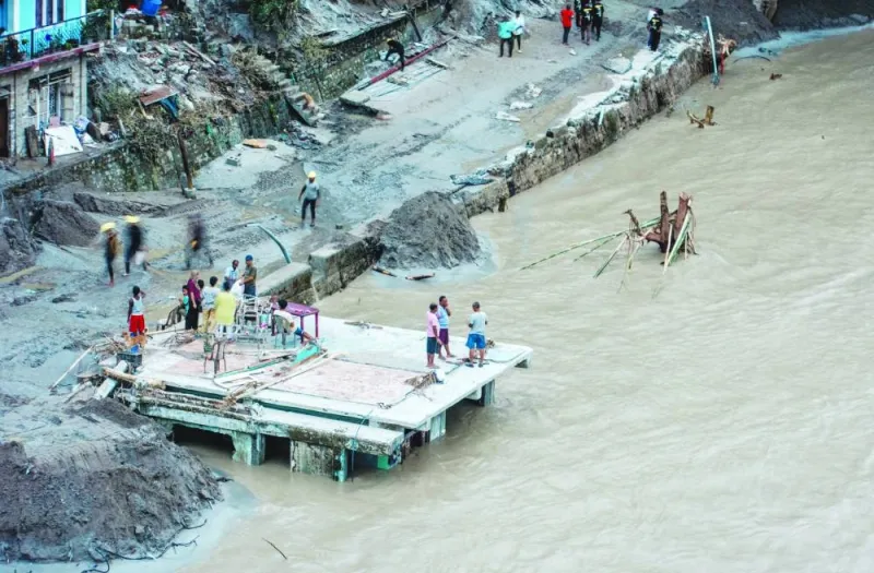 
People stand on the roof of a partially submerged house along the bank of Teesta River, in Teesta Bazaar, Kalimpong District, West Bengal, India. 