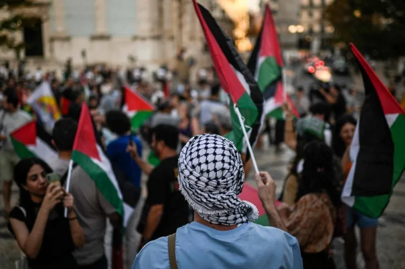 A protestor with a keffieh waves a Palestinian flag during a rally in support of Palestinians at Camoes square in Lisbon Monday. AFP