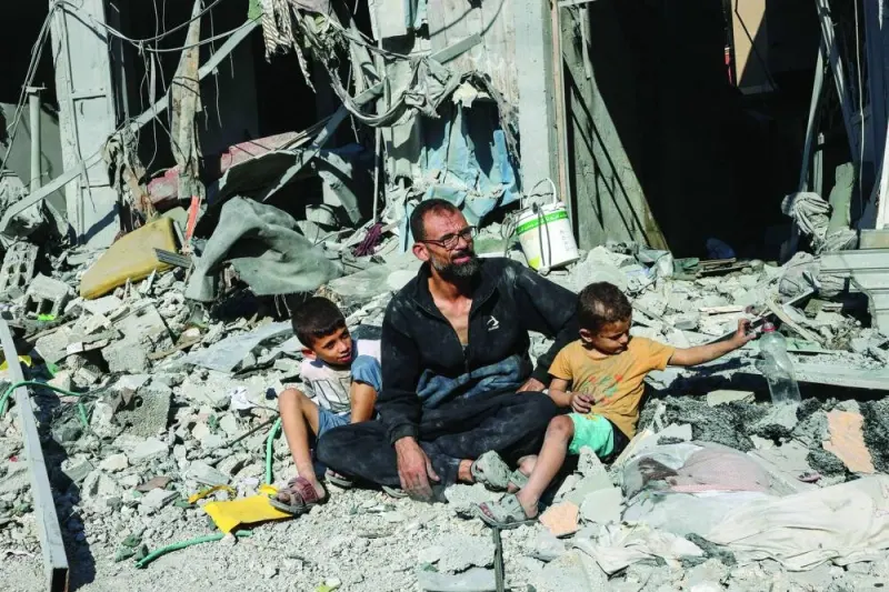 A man sits with members of his family outside a building destroyed in an Israeli air strike in Rafah in the southern Gaza Strip.