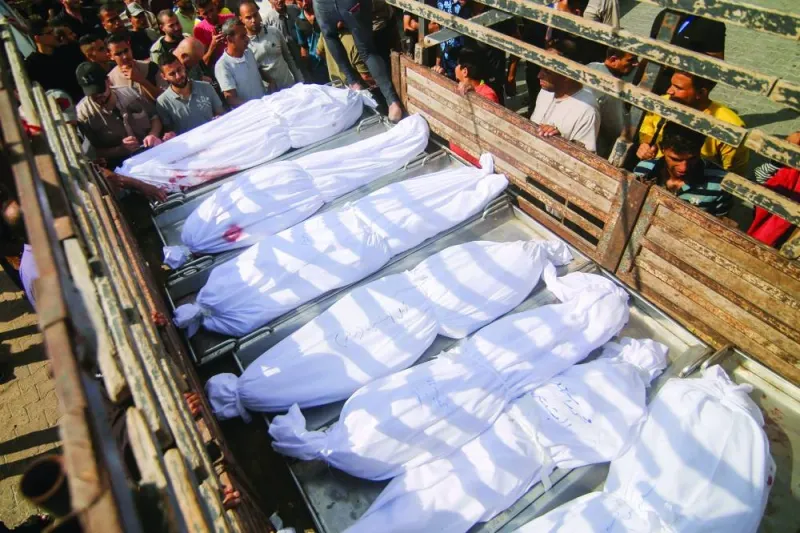 
Mourners look at the covered bodies of the Abu al-Rish family, killed during an Israeli air strike in Khan Yunis, on the southern Gaza Strip. 