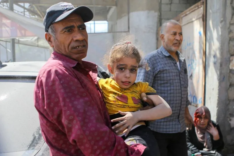 A Palestinian man carries a girl hurt in Israeli strikes in Gaza CitySunday. REUTERS