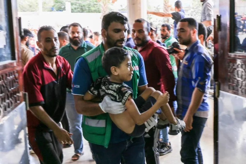 A Medic carries a Palestinian child injured during Israeli air strikes into a hospital in Khan Yunis in the southern of Gaza Strip, Monday, AFP