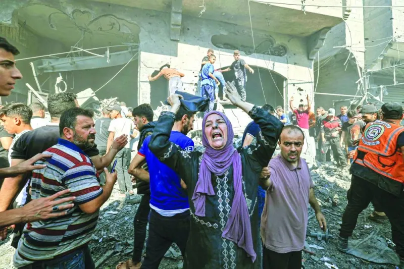 
A Palestinian woman reacts as others rush to look for victims in the rubble of a building following an Israeli strike in Khan Yunis in the southern Gaza Strip, yesterday. 