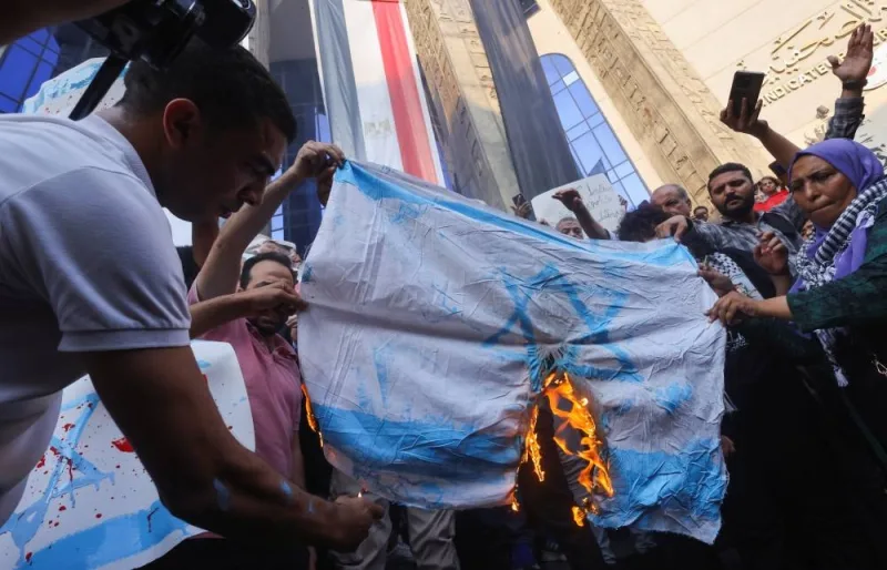 Demonstrators burn a banner depicting the Israeli flag during a protest against Israel and the USA in support of Palestinians for those killed in a blast at Al-Ahli hospital in Gaza that Israeli and Palestinian officials blamed on each other, amid the ongoing conflict between Israel and Hamas, in Cairo, Egypt, Wednesday. REUTERS