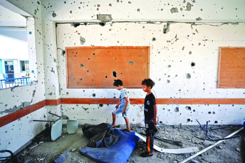 Boys stand in a shrapnel-pocked room inside a UN-run school in the refugee camp of Al-Maghazi in the central Gaza Strip, a day after at least six people were killed in a reported Israeli strike.