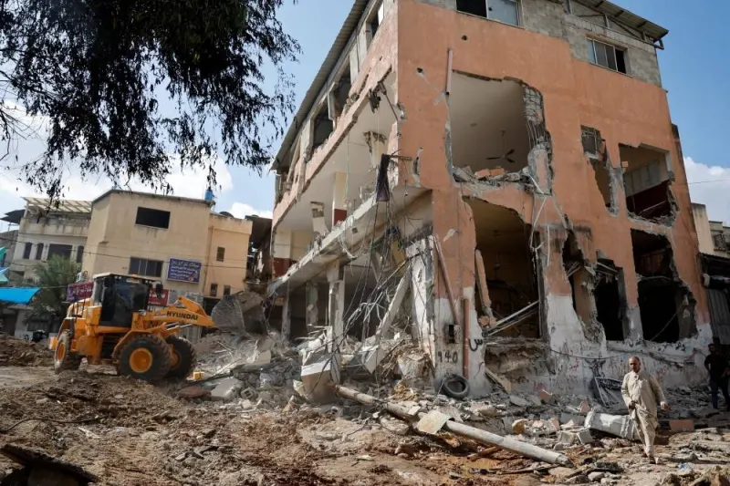 Palestinians walk next to a damaged building following an Israeli raid in Tulkarm in the Israeli-occupied West Bank Friday. REUTERS