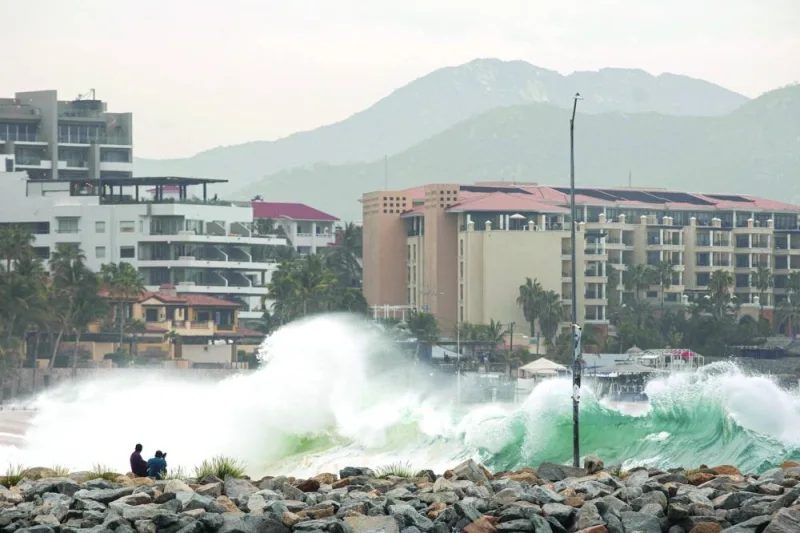 
People observe waves breaking on the beach as Hurricane Norma barrels towards Baja California. 