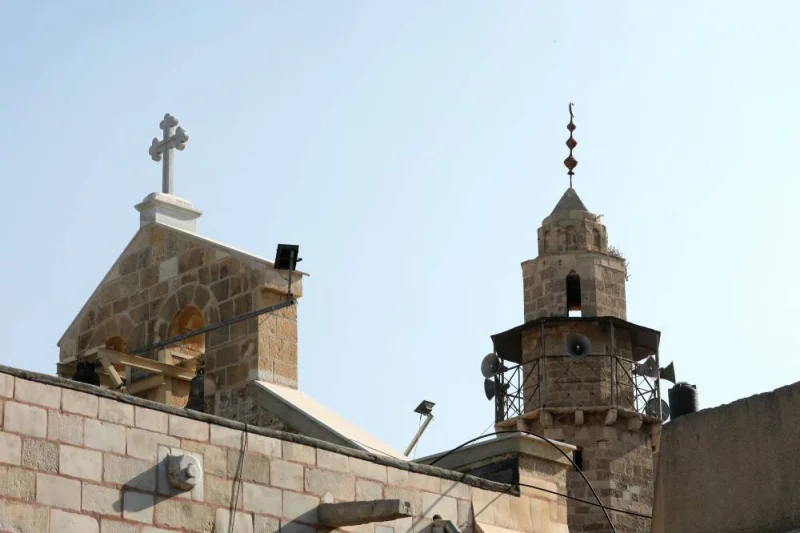 The rood cross of the Greek Orthodox Saint Porphyrius Church (L), the oldest church still in use in Gaza, is pictured next to the minaret of a mosque, the day after the church was damaged in a strike in Gaza City Friday. AFP