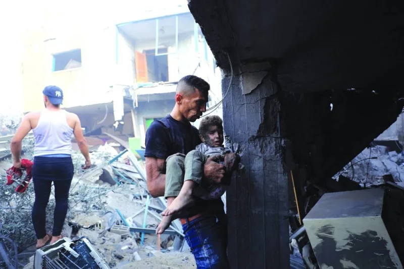 
A man carries a child as Palestinians search for casualties at the site of an Israeli strike on a residential building in Gaza City yesterday. 