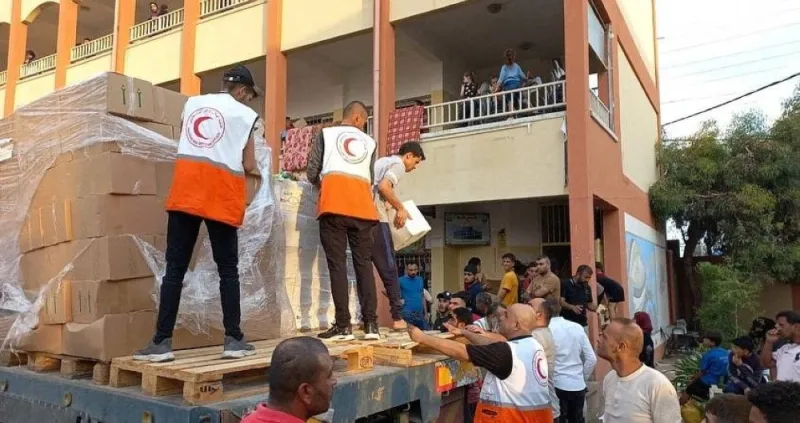 Members of the Palestine Red Crescent Society distribute aid to people in Deir al-Balah, in the central Gaza Strip.  Palestine Red Crescent Society/Handout via REUTERS