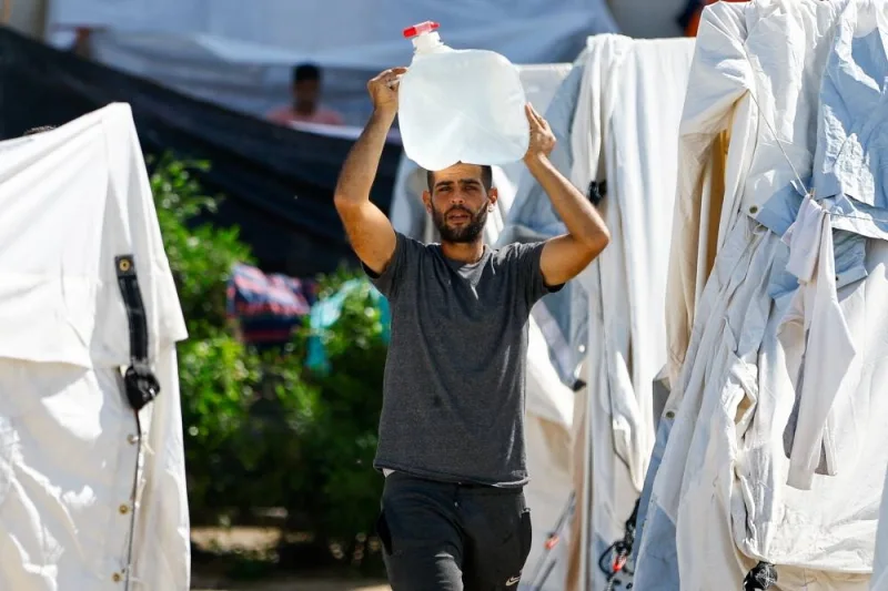 A man carries a container as displaced Palestinians, who fled their houses amid Israeli strikes, take shelter at a tent camp at a United Nations-run centre, in Khan Younis in the southern Gaza Strip, on Monday. REUTERS