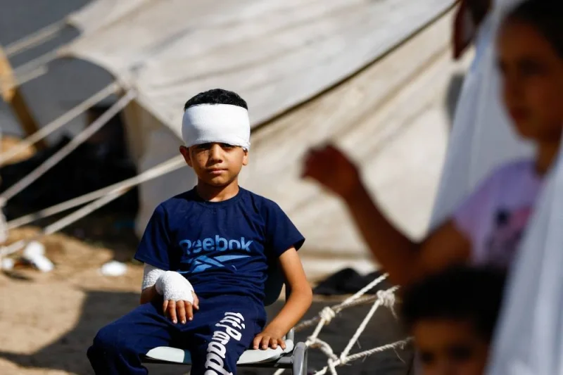 An injured boy sits as displaced Palestinians, who fled their houses amid Israeli strikes, take shelter at a tent camp at a United Nations-run centre, in Khan Younis in the southern Gaza Strip, on Monday. REUTERS