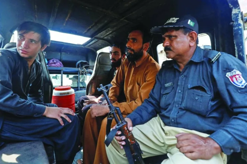 
A police officer sits with detained Afghan nationals, who according to them were undocumented, as they shift them to a holding centre, after Pakistan gave the last warning to undocumented migrants to leave, in Karachi, yesterday. (Reuters) 