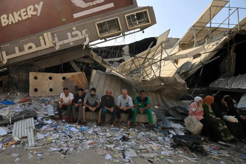 People sit in front of a bakery that was partially destroyed in an Israeli strike, in the Nuseirat refugee camp in the central Gaza Strip, on Thursday. AFP
