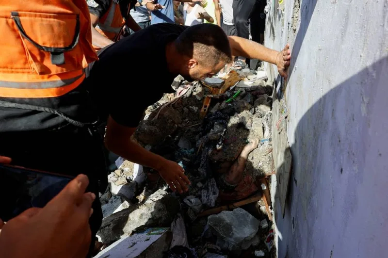 A man looks at the body covered in rubble at the site of Israeli strikes on a residential building, amid the ongoing conflict between Israel and Palestinian Islamist group Hamas, in Khan Younis in the southern Gaza Strip, on Saturday. REUTERS
