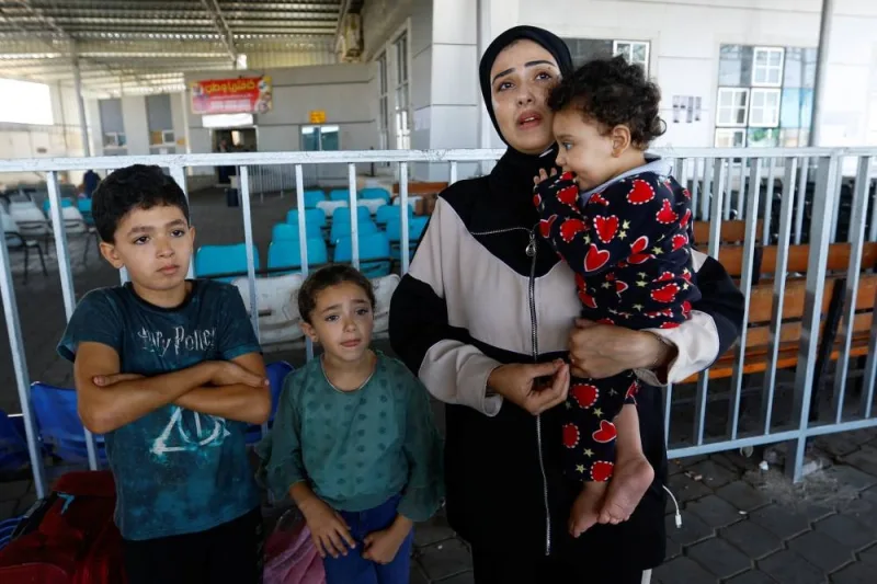 Palestinians, including foreign passport holders, wait at Rafah border crossing after evacuations were suspended following an Israeli strike on an ambulance, in Rafah in the southern Gaza Strip, Sunday. REUTERS
