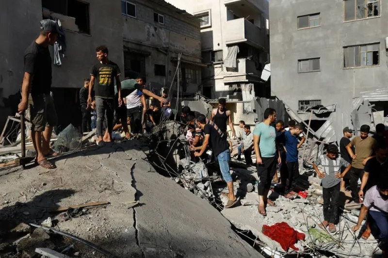 Palestinians gather at the site of an Israeli strike on a house, in Khan Younis in the southern Gaza Strip, Monday. REUTERS
