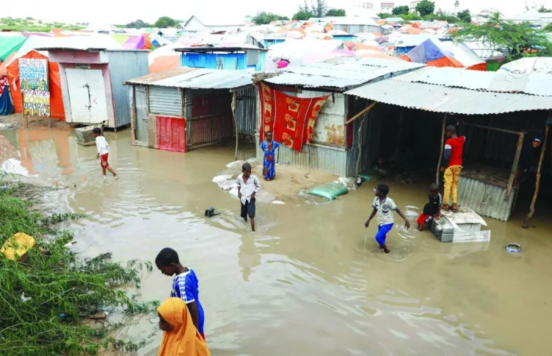 
Internally displaced Somali children wade through flood waters outside their makeshift shelters following heavy rains at the Al Hidaya camp for the internally displaced on the outskirts of Mogadishu, yesterday. 