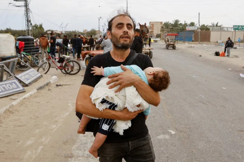A Palestinian man holding a child flees north Gaza as they move southward, as Israeli tanks roll deeper into the enclave in the central Gaza Strip, on Monday. REUTERS