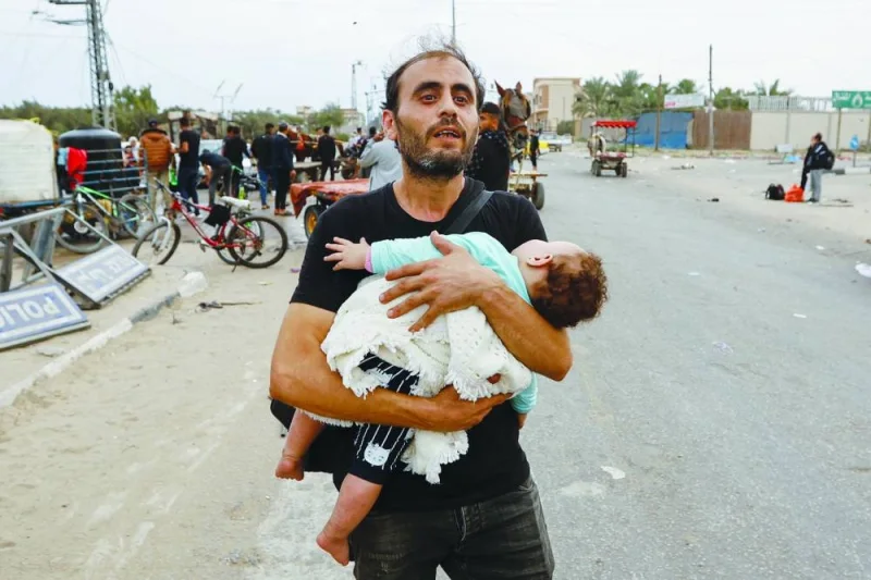 A Palestinian man holding a child flees north Gaza as they move southward, as Israeli tanks roll deeper into the enclave, amid the ongoing conflict, in the central Gaza Strip.