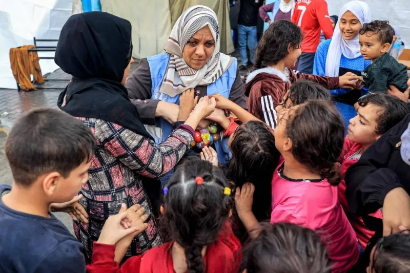 Workers of the United Nations Relief and Works Agency for Palestine Refugees in the Near East (UNRWA) distribute sweets to children at an UNRWA school in Rafah in the southern Gaza Strip on Tuesday, where internally displaced Palestinians have taken refuge amid ongoing battles between Israel and the Palestinian militant group Hamas.  AFP