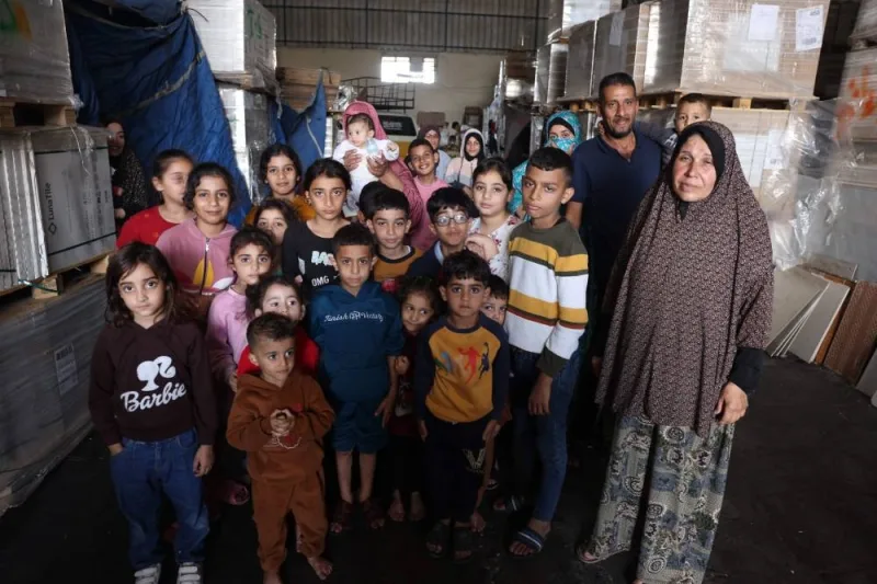 Children and their families pose for a photograph inside a large ceramic&#039;s shop where they are currently living in Bureij, in the central of Gaza Strip, on Tuesday. AFP