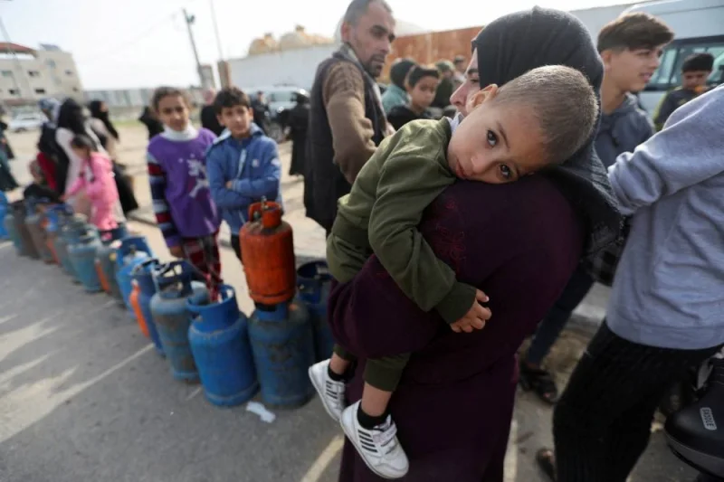 A woman carries a child as Palestinians gather to fill liquid gas cylinders, during a temporary truce between Hamas and Israel, in Rafah in the southern Gaza Strip, on Saturday. REUTERS