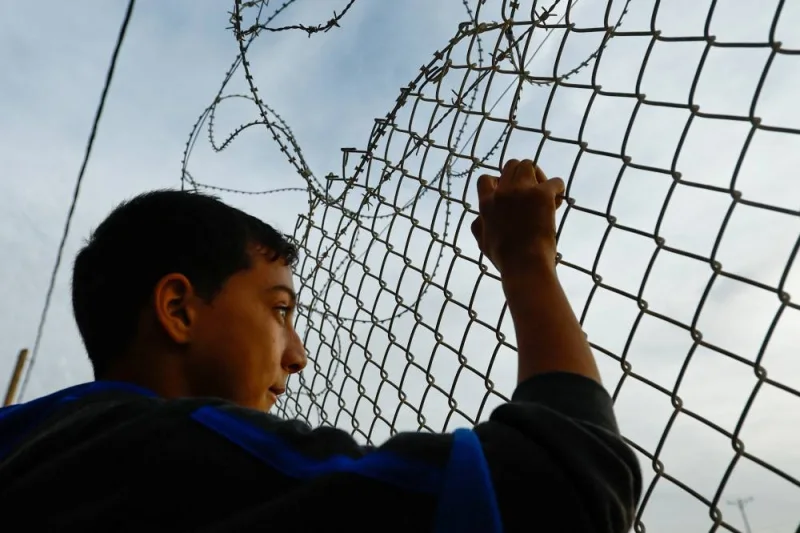 A child holds a fence at the Rafah border, as Hamas is expected to release hostages on Saturday. REUTERS