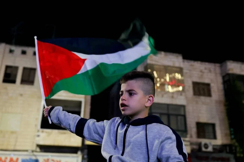 A child waves a flag as released Palestinian prisoners leave the Israeli military prison, Ofer, amid a hostages-prisoners swap deal between Hamas and Israel, in Ramallah in the Israeli-occupied West Bank on Sunday. REUTERS