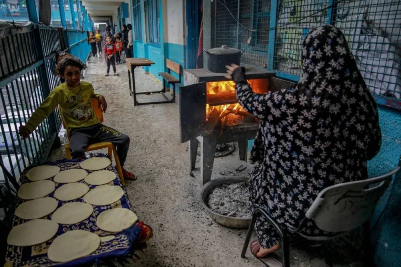 A Palestinian woman and a child cook bread at a UNWRA school used as shelter in Gaza City on Monday, on the fourth day of a truce in fighting between Israel and Hamas. AFP
