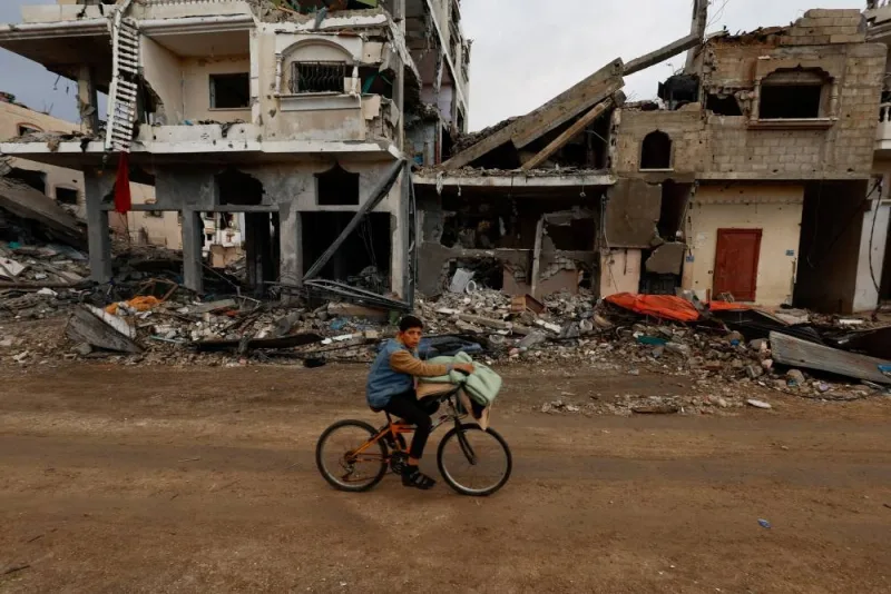 A Palestinian rides a bicycle next to the rubble of a house hit in an Israeli strike during the conflict, amid a temporary truce between Hamas and Israel, in Khan Younis in the southern Gaza Strip, on Monday. REUTERS