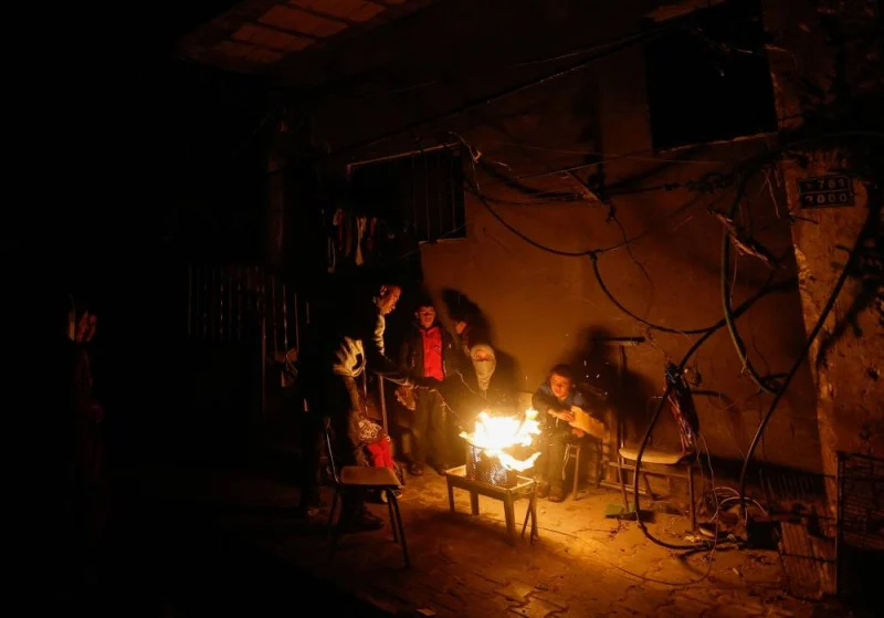 Palestinians sit next to a fire, amid a temporary truce between Hamas and Israel, in Khan Younis in the southern Gaza Strip, on Monday. REUTERS