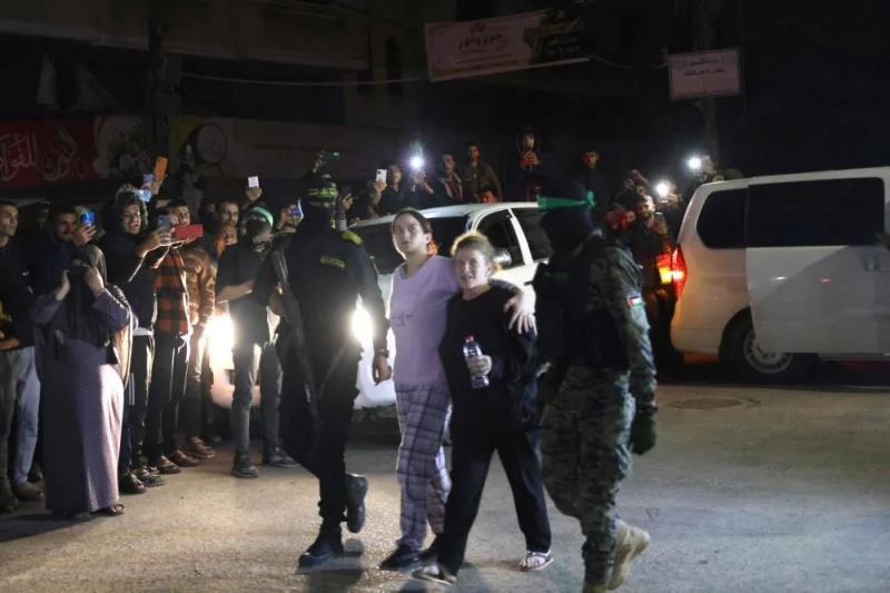 Hamas fighters accompany newly released hostages before handing them over to the Red Cross in Rafah, in the southern Gaza Strip on Tuesday. REUTERS