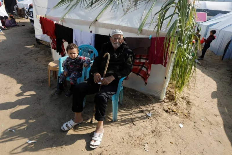 Displaced Palestinian man Abu Wael Nasrallah sits next to his grandchild near their tent where they take shelter at Nasser hospital in Khan Younis, in the southern Gaza Strip, on Saturday. REUTERS
