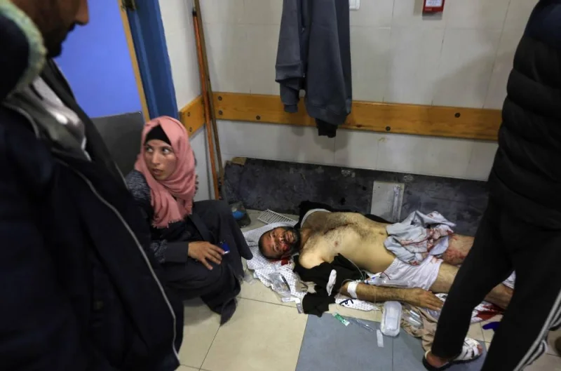 A woman sits by an injured man lying on the floor at the Nasser hospital in Khan Yunis in the southern Gaza Strip, following Israeli strikes on Sunday. AFP